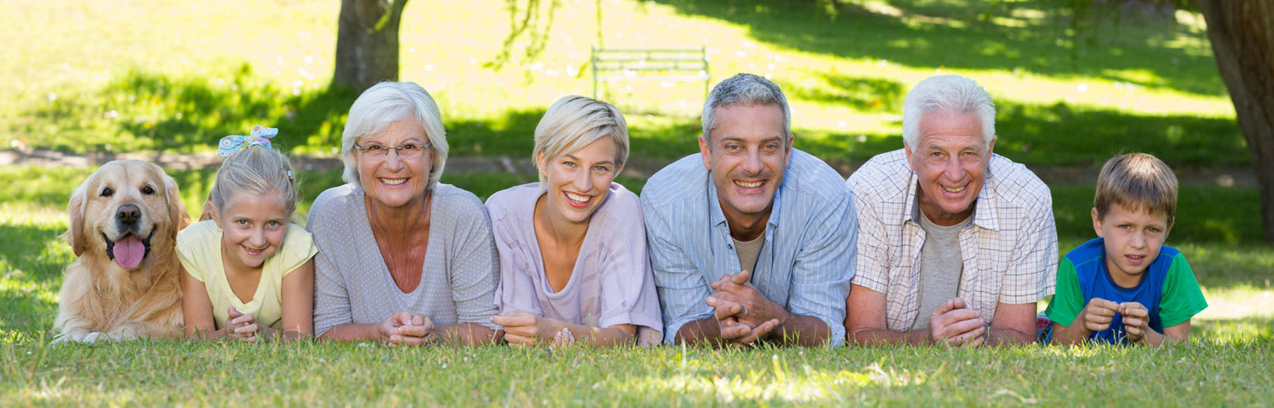Õnnelik pere, kes naeratades päikesepaistelisel päeval on koos koeraga pargis pilti tegemas
