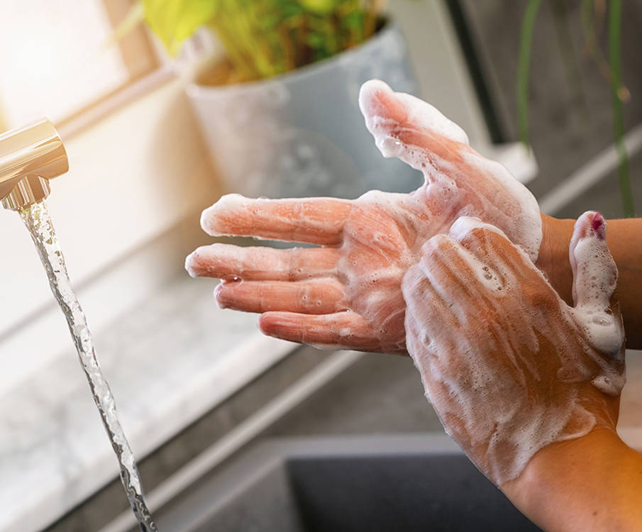 Woman washes her hands with soap and running tap water