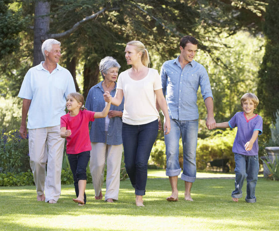 A family of several generations walks barefoot outdoors in sunny weather